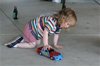 Little Girl In Striped Shirt Pushing Toy Car